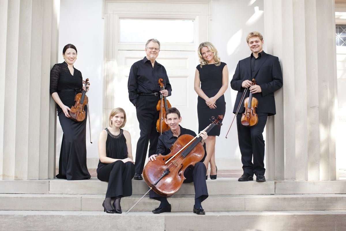 Classical musicians pose on a stairway